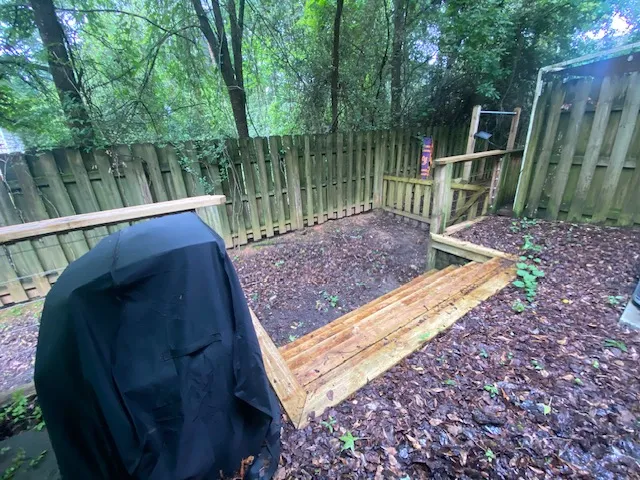 Secure yard featuring a wood fence, ample natural foliage, and outdoor stairs.