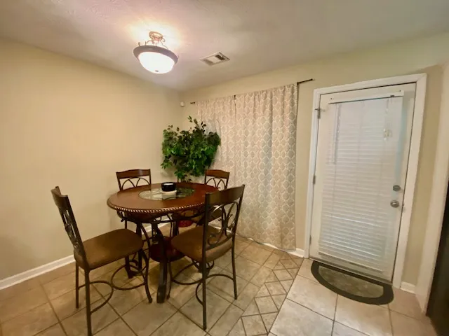 Warm and inviting dining area features tiled flooring and an exterior door leading to outdoor space.