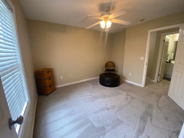 A well-lit bedroom with ceiling fan lighting and access to a private bathroom.