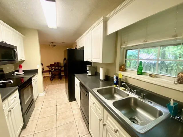 A galley kitchen with abundant counter space and bright white cabinetry opens to a dining area.