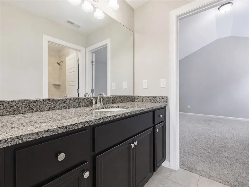 Double vanity featuring granite counters and elegant black cabinetry provides a luxurious start to every day.