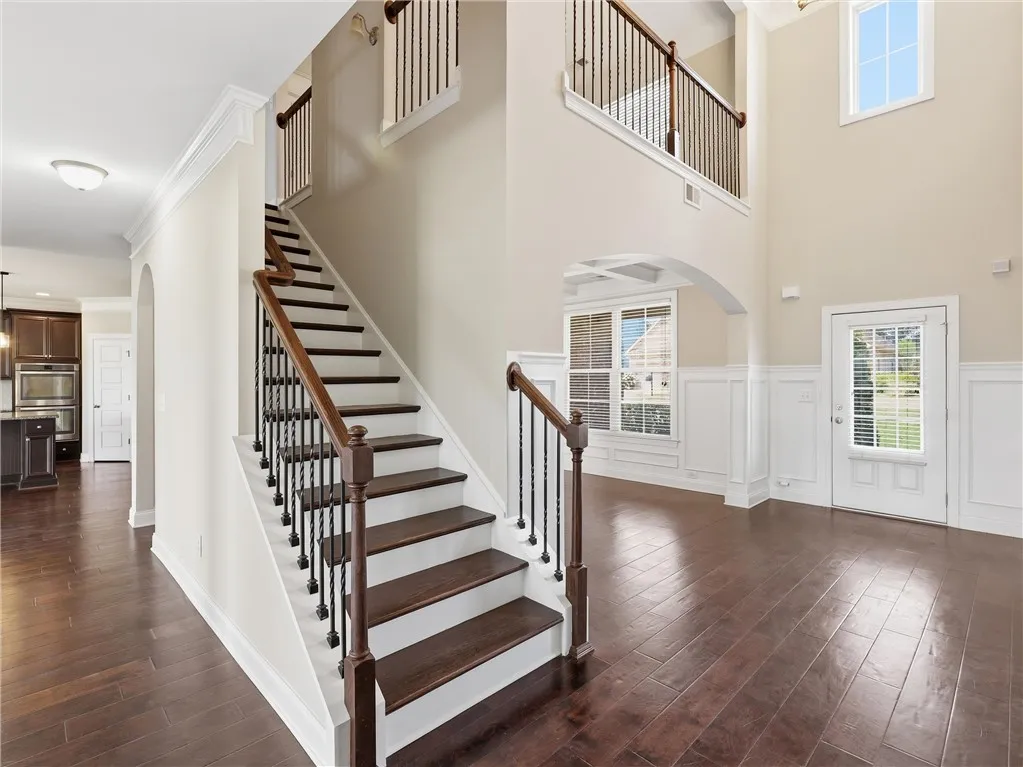 Grand two-story foyer boasts rich hardwood floors and a striking staircase with wrought iron balusters.