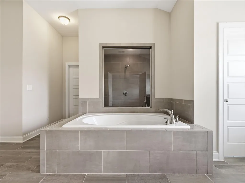An inviting soaking tub takes center stage, complemented by a sleek, glass-enclosed shower.