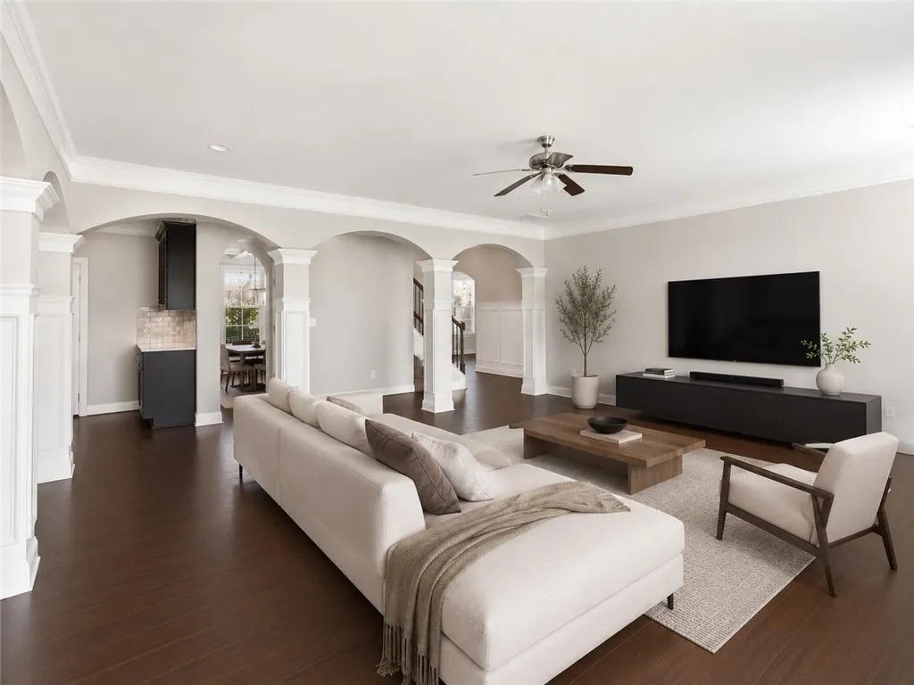 Rich hardwood floors flow through an open layout, connecting living spaces beneath elegant arched walkways.