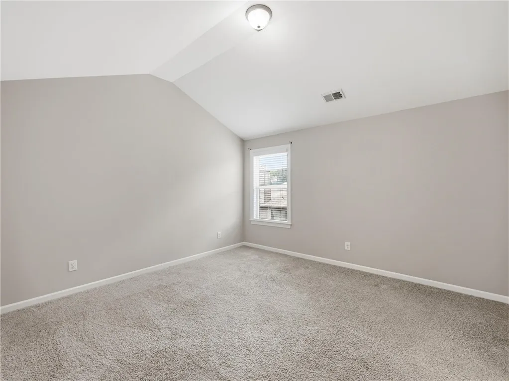 A well-lit bedroom offering a cozy retreat with soft carpeting and an inviting atmosphere.