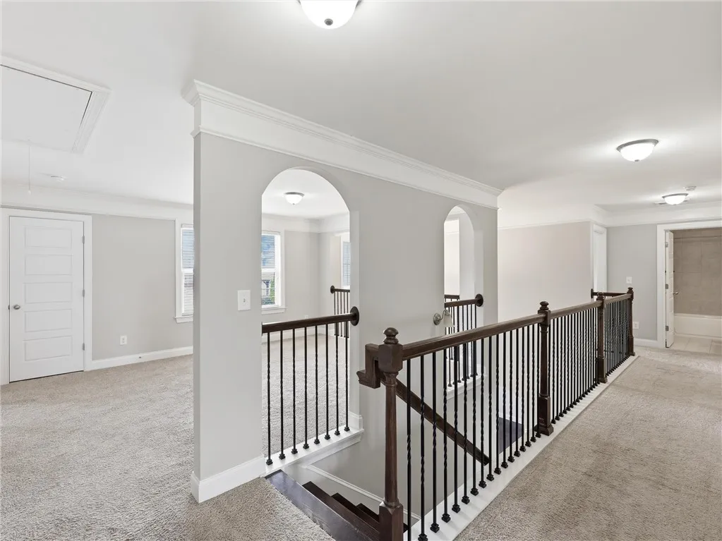 Carpeted upper-level landing with decorative arched entries and a rich wooden banister.