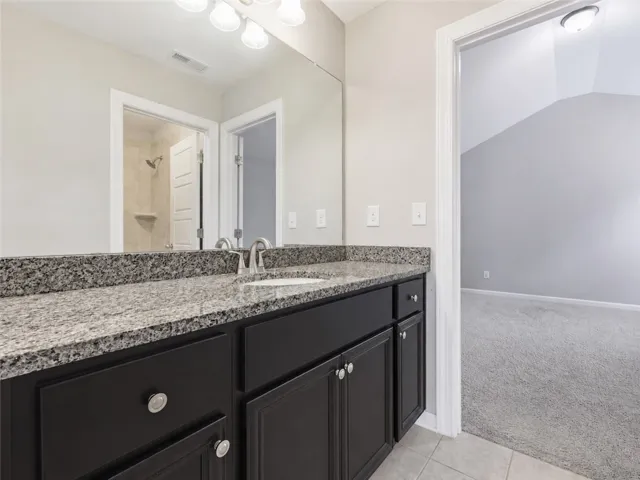 Double vanity featuring granite counters and elegant black cabinetry provides a luxurious start to every day.