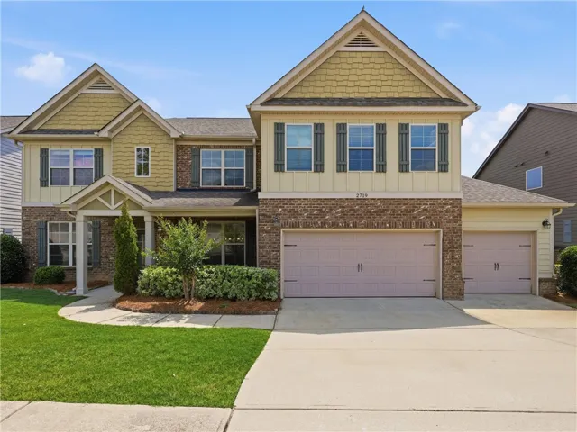 A well-maintained facade features a mix of brick and siding, complemented by neatly manicured landscaping and a concrete driveway.