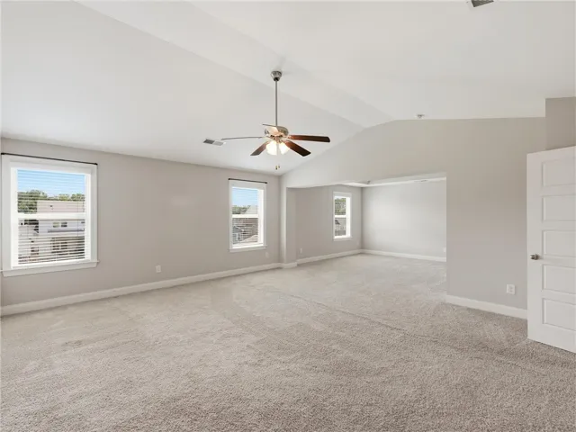 A spacious bedroom featuring high vaulted ceilings and multiple windows for abundant light.