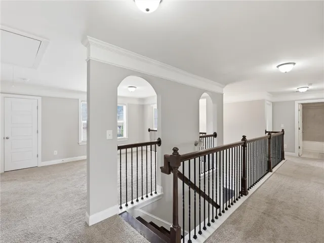 Carpeted upper-level landing with decorative arched entries and a rich wooden banister.
