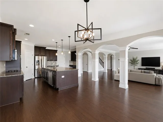 An open floorplan seamlessly connects the kitchen and living areas, highlighted by rich hardwood flooring and elegant archways.