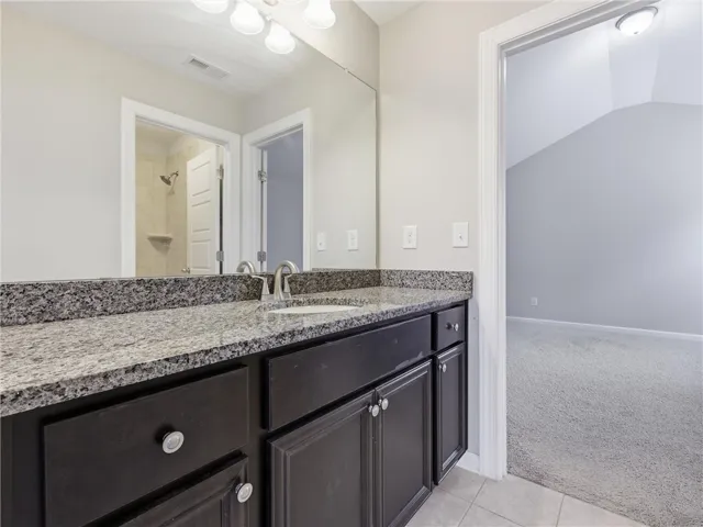 Jack and Jill Bathroom with stone counters provides ample space and sleek style for daily routines.
