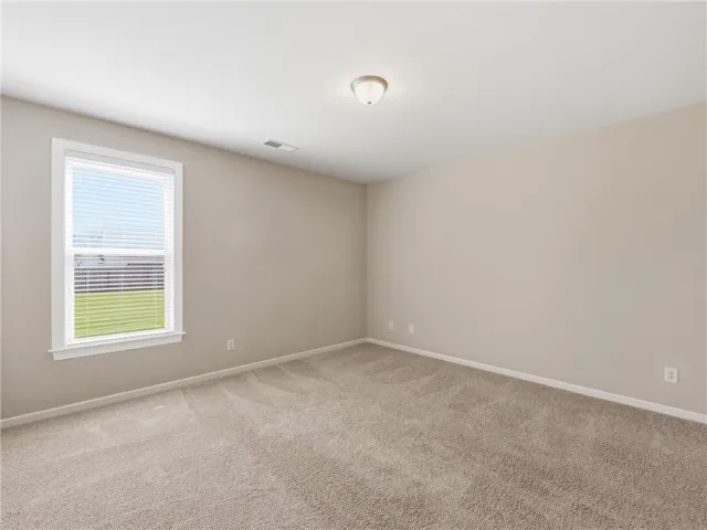 1st flr - Guest Bedroom 
An inviting room awaits personalization, featuring soft carpeting and natural light from a well-placed window.