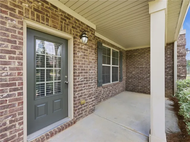 A welcoming front porch features classic brick, durable concrete flooring, and a glass-paneled entry door.