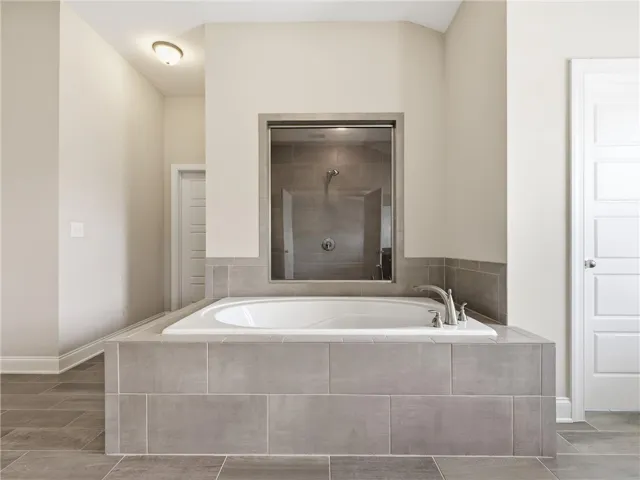 An inviting soaking tub takes center stage, complemented by a sleek, glass-enclosed shower.