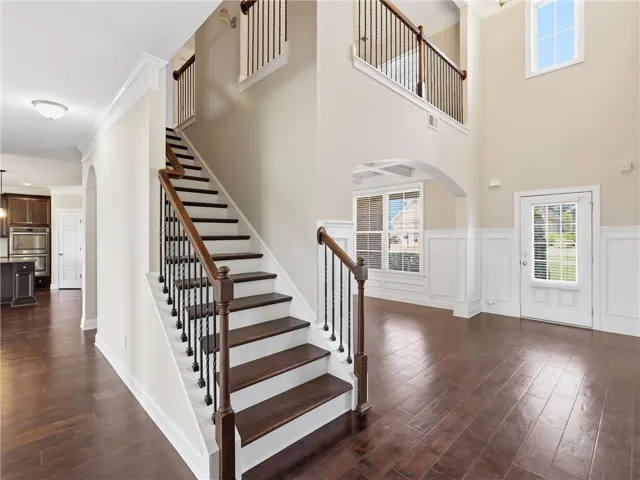 Grand two-story foyer boasts rich hardwood floors and a striking staircase with wrought iron balusters.