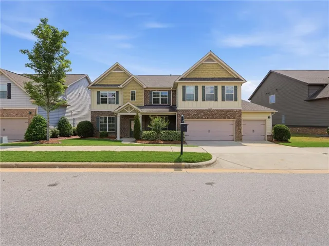 A classic two-story home with a mix of brick and siding, featuring a well-maintained lawn and an attached double garage.