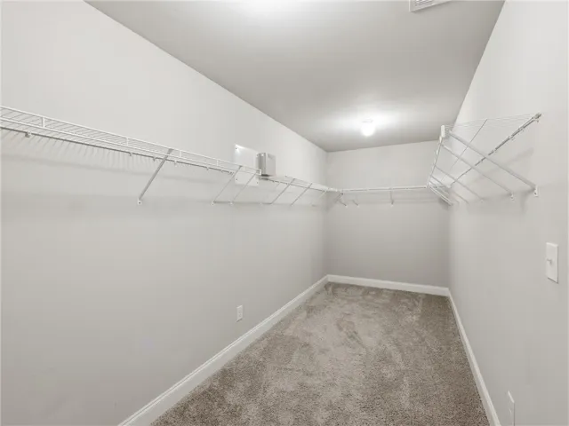 Ample wire shelving and soft carpeting define this generously sized walk-in closet.