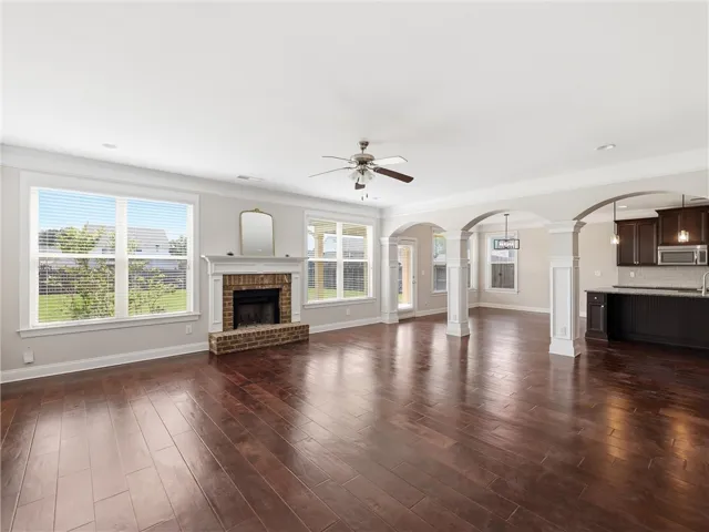 Rich hardwood floors unite an open-concept living space with an inviting fireplace, perfect for gathering.