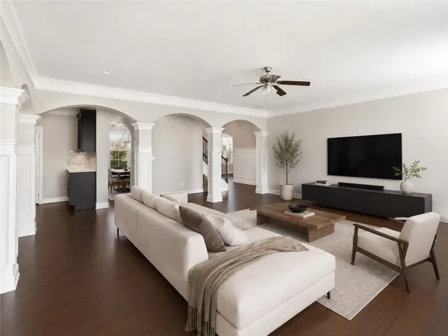 Rich hardwood floors flow through an open layout, connecting living spaces beneath elegant arched walkways.
