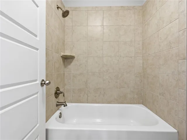 A well-appointed bathroom features a bathtub and shower combination with tiled walls and bronze fixtures.