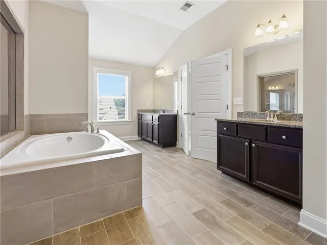 Indulge in this bathroom featuring a large soaking tub and dual vanity sinks with ample storage.