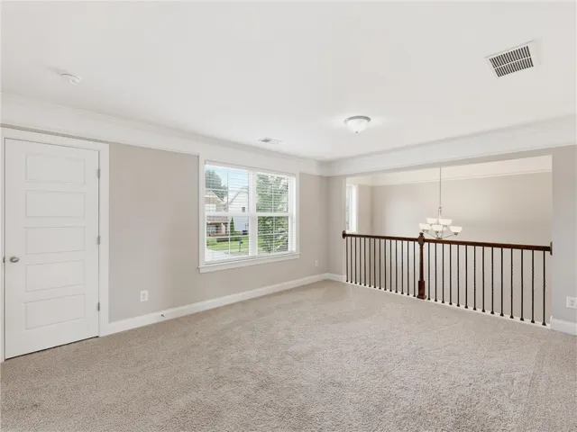 A well-lit loft space featuring plush carpeting and a sturdy railing overlooking the lower level.