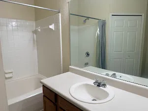 A well-lit bathroom features a functional shower-tub combination.