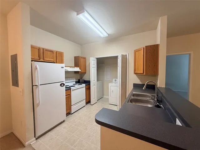 Functional kitchen with ample cabinet space, a practical double-basin sink, and integrated laundry access.