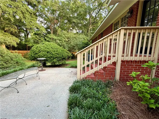 A private patio space adjoins a brick exterior with inviting porch access, enveloped by mature foliage.