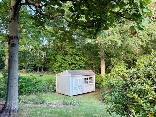 Abundant greenery, surrounds additional storage space offering a functional addition to the property.