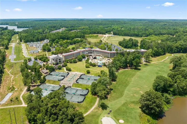 An aerial perspective reveals a luxurious resort community with a large pool area, tennis courts, and a pristine golf course.