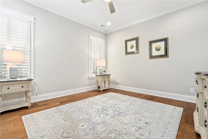 Well-lit room featuring rich hardwood flooring and elegant crown molding, creating an inviting atmosphere.