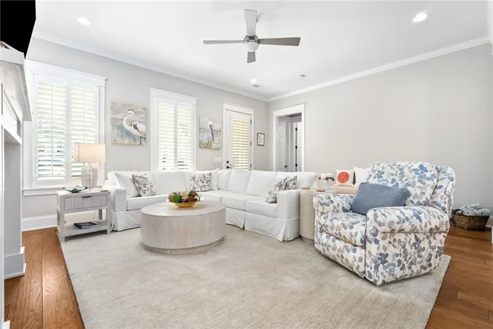 Relax in this comfortable living room featuring hardwood floors and a cozy ceiling fan.