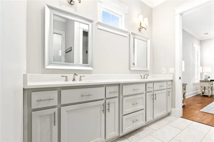 Double vanity with stone counters provides ample space and elegant fixtures in this well-appointed bathroom.