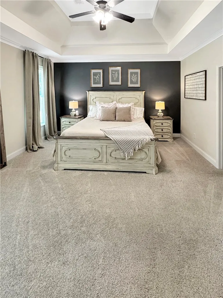 Luxurious comfort awaits in this well-appointed bedroom featuring a tray ceiling and plush carpeting.