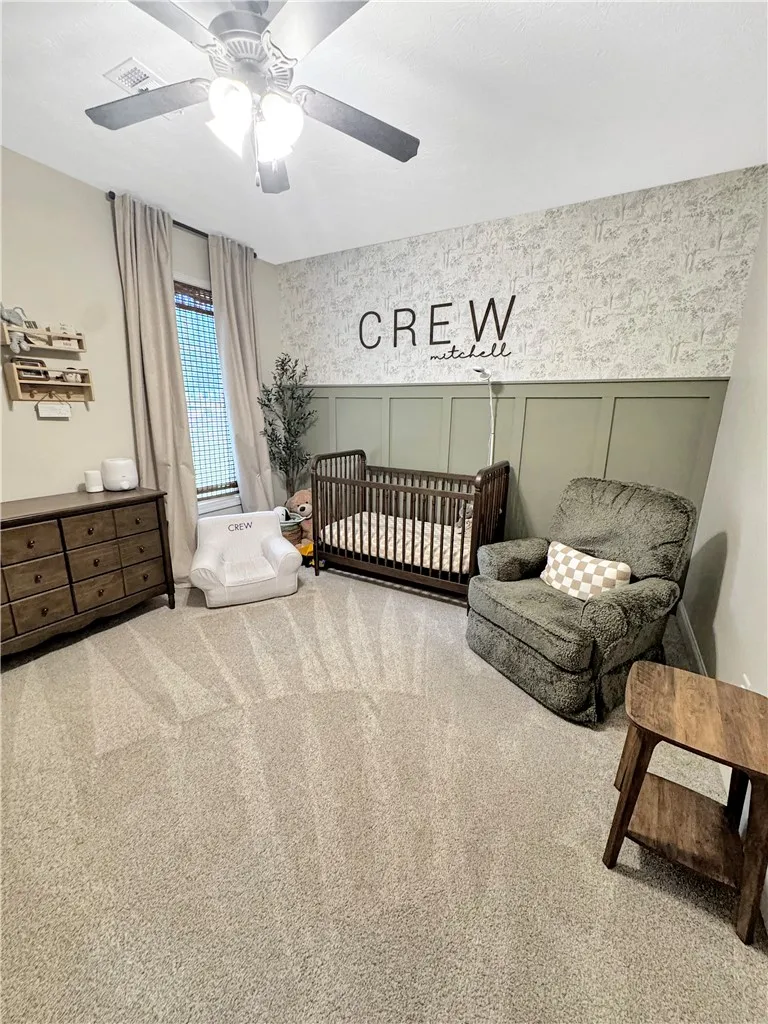 A comforting nursery with a delightful wall treatment and plush carpeting.