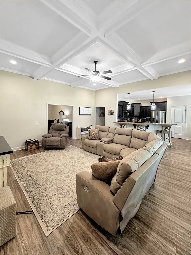 An inviting open-concept space features warm wood-toned flooring and an elegant coffered ceiling.
