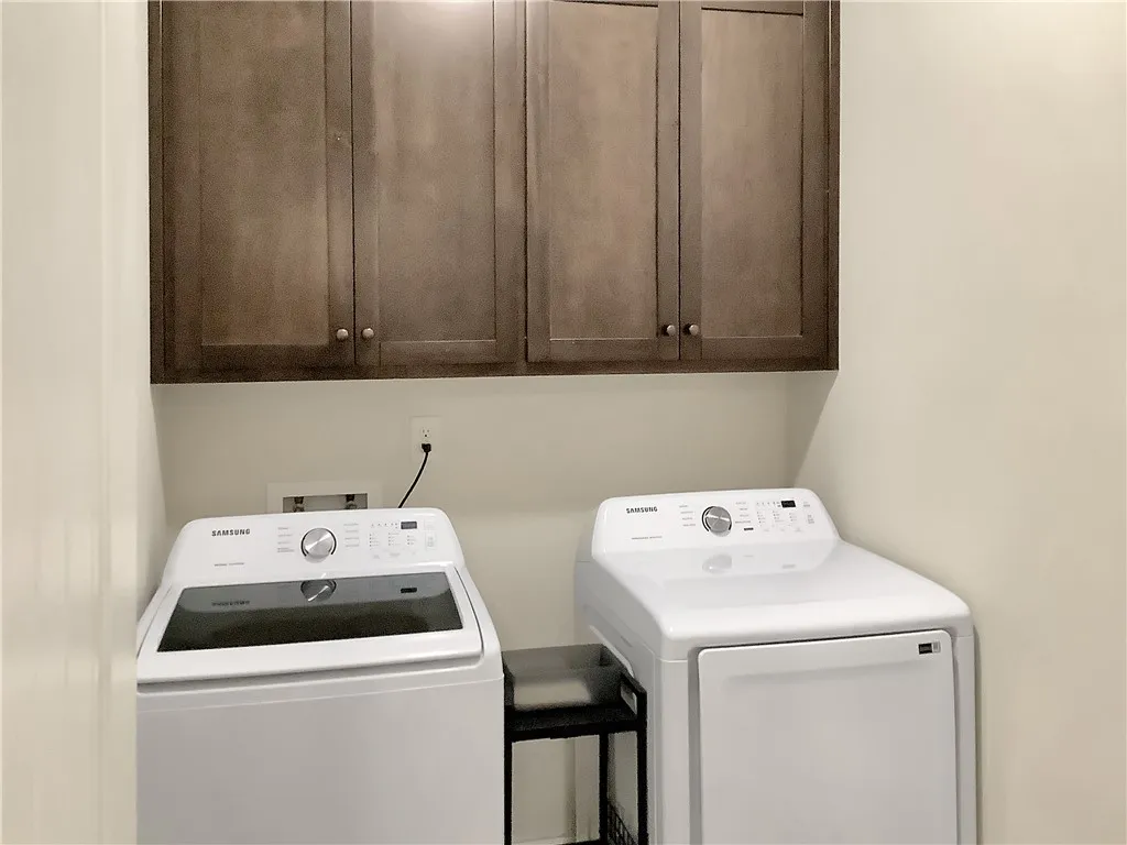 Streamlined laundry area with functional cabinetry offers effortless home management.