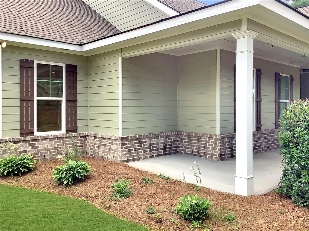 A welcoming front porch features sturdy columns and classic brickwork, complemented by tasteful landscaping.