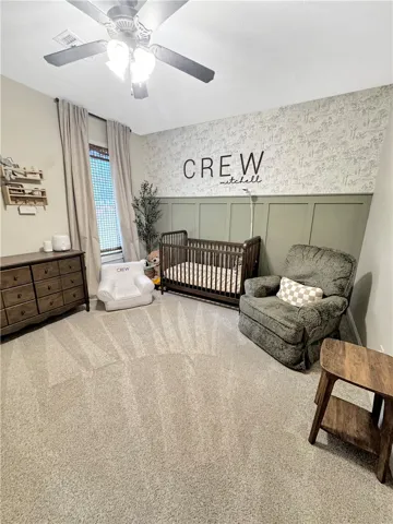 A comforting nursery with a delightful wall treatment and plush carpeting.