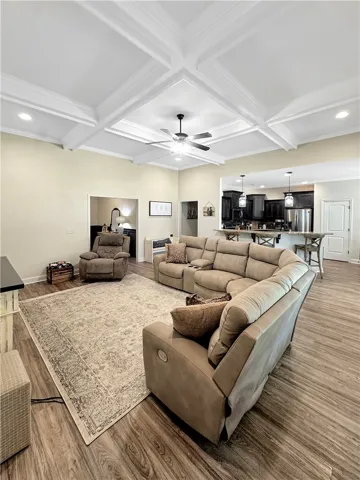 An inviting open-concept space features warm wood-toned flooring and an elegant coffered ceiling.