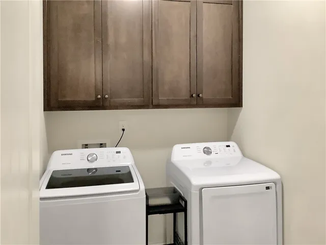 Streamlined laundry area with functional cabinetry offers effortless home management.