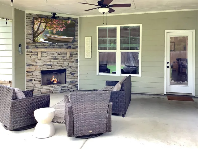 An inviting covered patio featuring a stone-clad fireplace, ideal for outdoor entertainment.