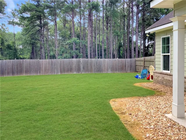 A verdant lawn creates a peaceful backyard retreat, enclosed by a private fence and natural tree line.