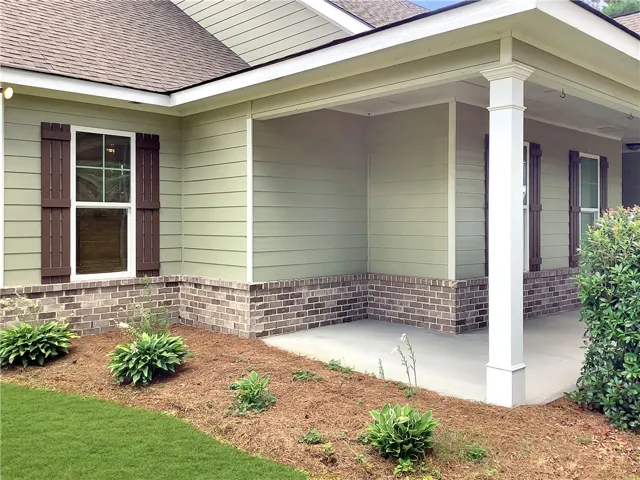 A welcoming front porch features sturdy columns and classic brickwork, complemented by tasteful landscaping.