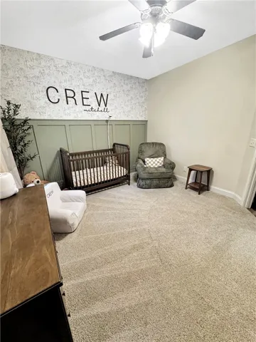 A well-lit room featuring wainscoting and plush carpet, ideal for a nursery.