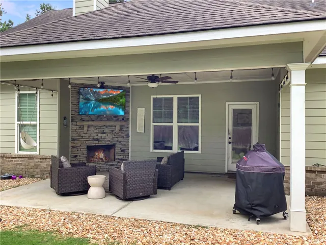 An inviting covered patio features a stone fireplace for cozy evenings outdoors.