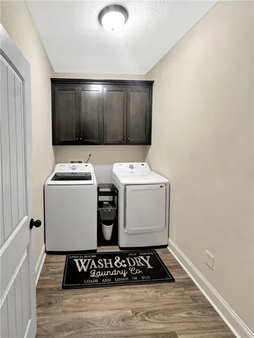 Functional laundry space featuring modern appliances and convenient overhead cabinetry.