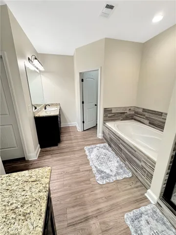 Relax and unwind in this well-appointed primary bathroom, boasting a spacious soaking tub and dual vanities with granite counters.
